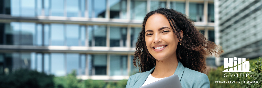 Woman standing outside an office building with Hilb Group logo on the bottom right of the image