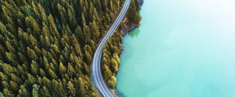 Aerial view of a lake alongside a road and forest