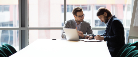 Two colleagues going over paperwork at a table in an office