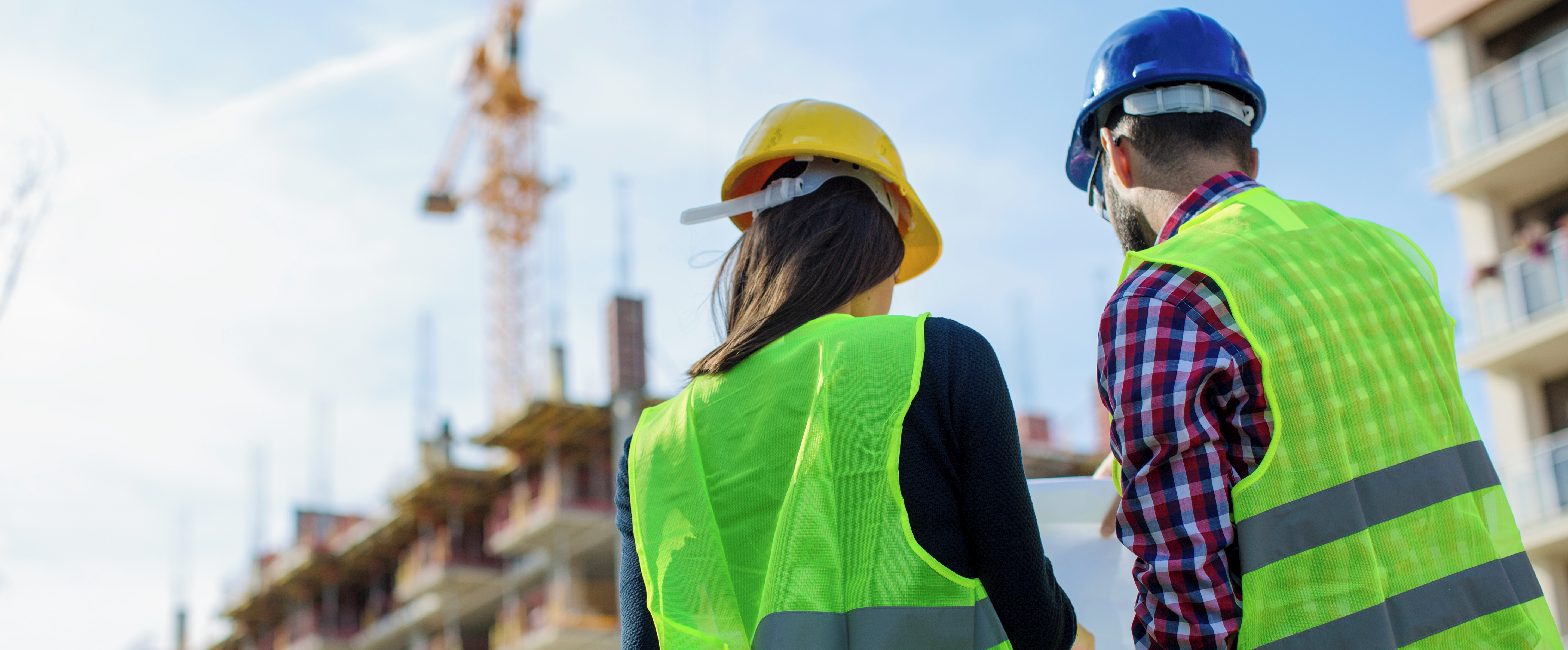 Two construction workers looking at blueprints on site