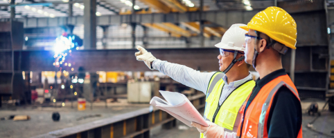 Two construction workers looking over blueprints indoors