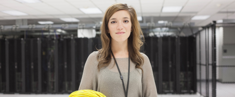 Woman standing in an office holding wires