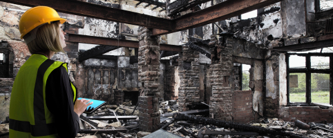 Construction worker assessing wildfire damage to a building