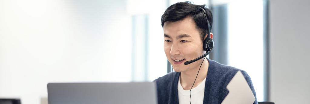 Man working on a laptop with a headset on in an office