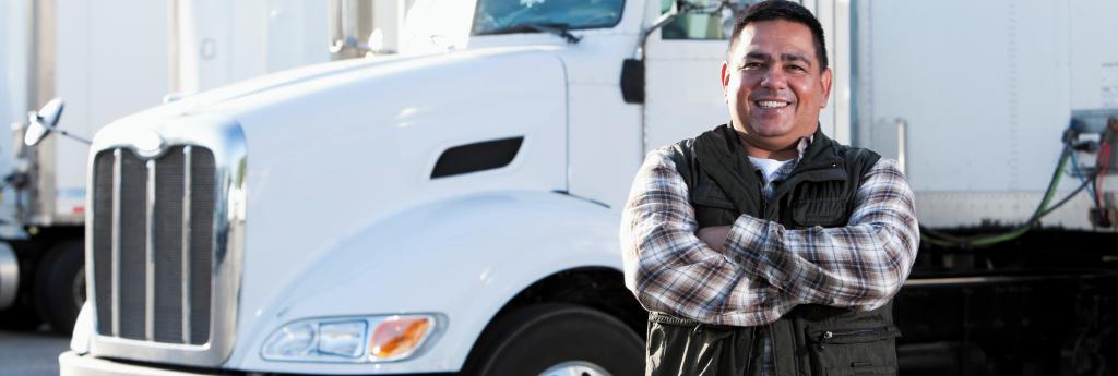 Truck driver standing in front of a truck in a parking lot