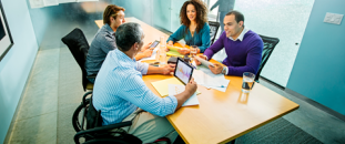 Colleagues talking around a desk in a meeting