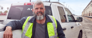Construction worker leaning on a pickup truck