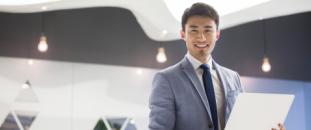 Businessman holding a laptop in an office and smiling 