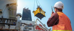 Construction worker watching with a walkie-talkie as a ship is loaded