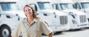 Female truck driver standing in front of a row of trucks