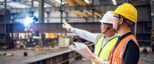 Two construction workers looking over blueprints indoors