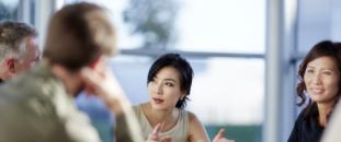 Colleagues sitting at a table in an office talking