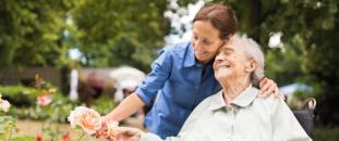 Nurse taking care of an elderly patient in a wheelchair outside