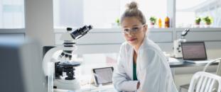 Scientist sitting at a desk and working with a microscope