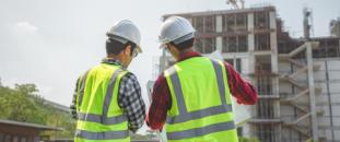 Construction workers looking over blueprints on site