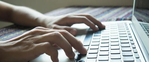 Hands typing on a laptop keyboard