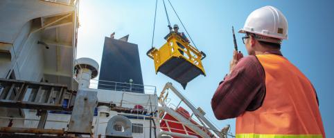 Construction worker watching with a walkie-talkie as a ship is loaded