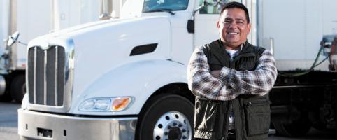 Truck driver standing in front of his truck in a parking lot