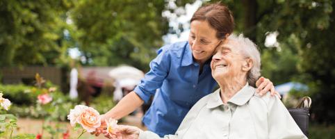 Nurse taking care of an elderly patient in a wheelchair outside